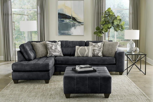 black sectional sofa in a living room with decorative pillows and a rug.