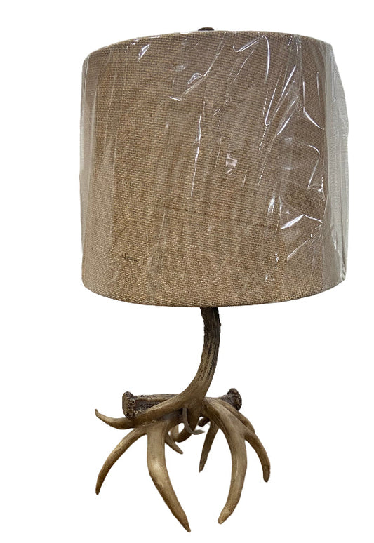 Lamp with natural antler base and burlap shade on a white background