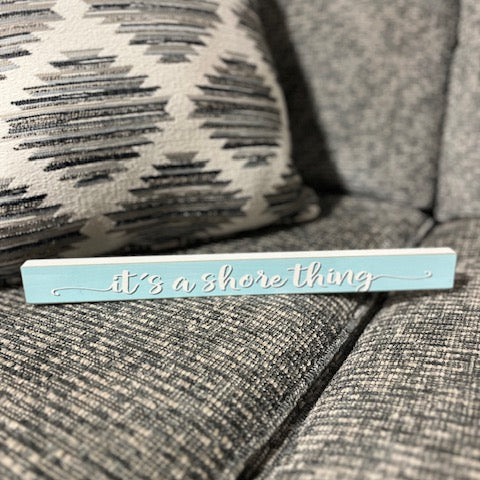 Decorative sign with 'it's a shore thing' text on a textured surface