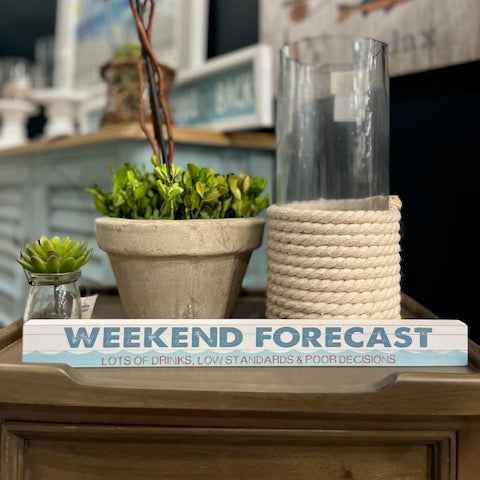 Decorative setup with plants and a sign reading 'Weekend Forecast' on a wooden surface.