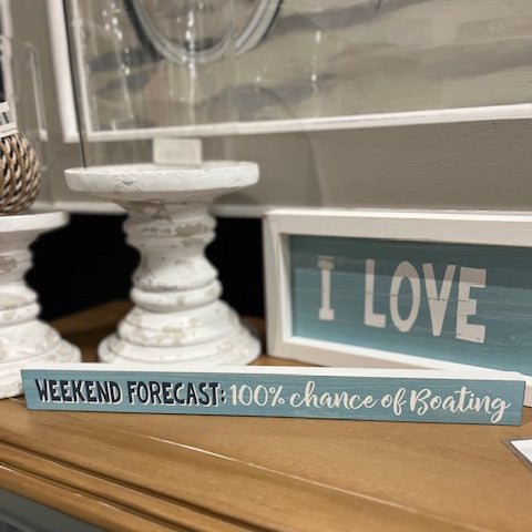 Decorative sign with 'I LOVE' and 'Weekend Forecast' text on a wooden surface.