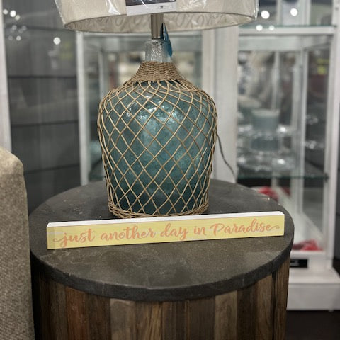 Decorative lamp with textured base and clear lampshade on a round wooden table.