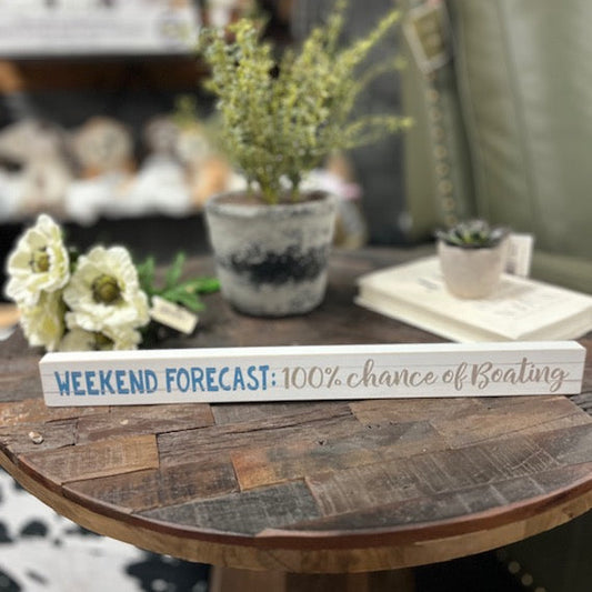 Decorative sign on a wooden table with plants and flowers in the background