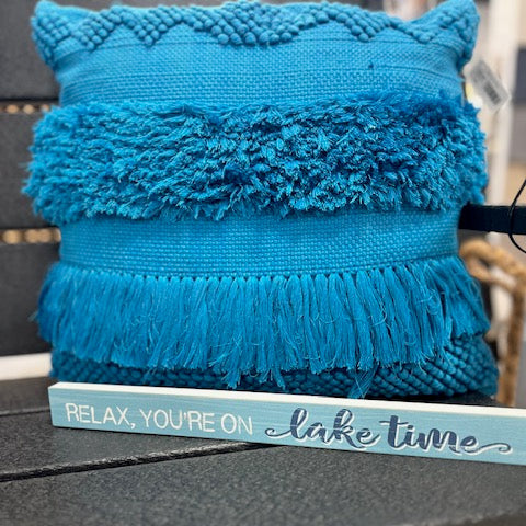 Blue textured pillow on a chair with a sign reading 'Relax, you're on lake time'.