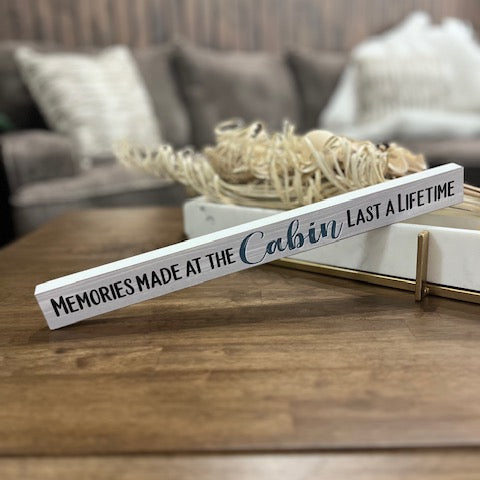 Decorative sign on a wooden surface with a blurred background of a living room.