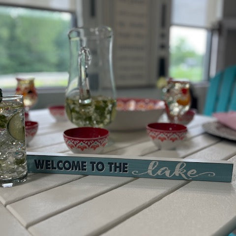 Table setting with 'Welcome to the Lake' sign in a casual dining area.