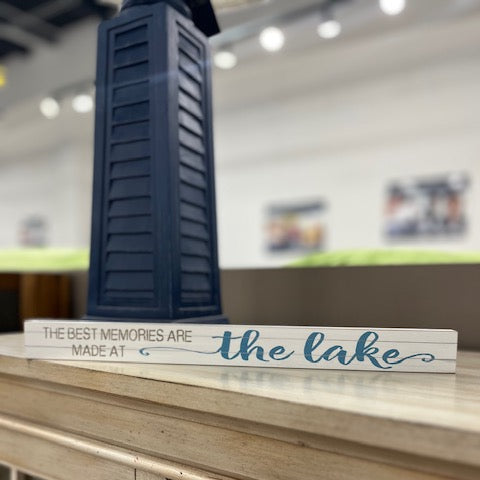 Decorative sign with 'The best memories are made at the lake' text on a wooden surface.