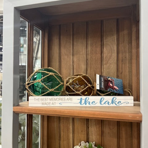 Decorative items on a wooden shelf with 'the lake' sign