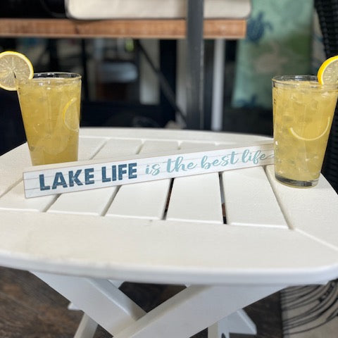 Two drinks with lemon slices on a table with 'Lake Life is the best life' sign.