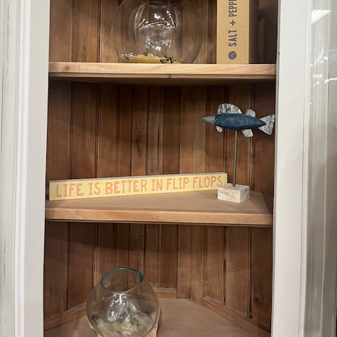 Wooden shelf with decorative items including a fish-shaped object and a bottle.