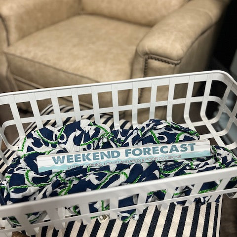 Basket with decorative items including a blue and white patterned pillow and a striped blanket on a chair.