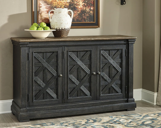 Dark wooden sideboard with decorative cross patterns on doors, placed against a wall with a painting and decor items.