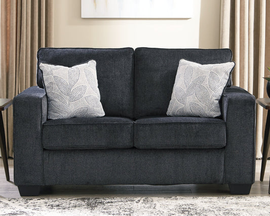 Gray loveseat with leaf-patterned cushions in a living room setting