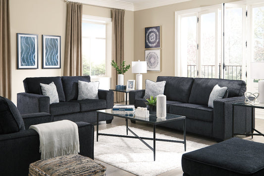 Modern living room with dark gray sofas, a glass coffee table, and decorative elements.