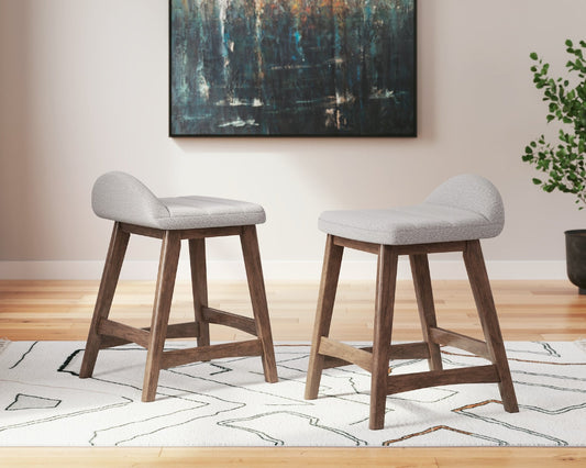 2 gray upholstered stools on a white rug with an abstract painting on the wall