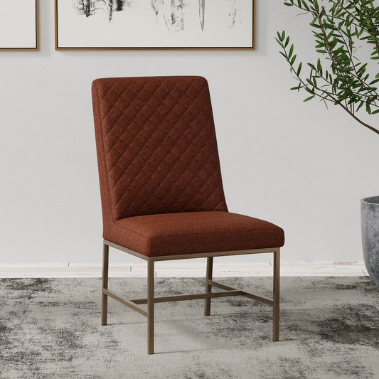 rust upholstered chair in a room with a white wall, framed pictures, and a plant.