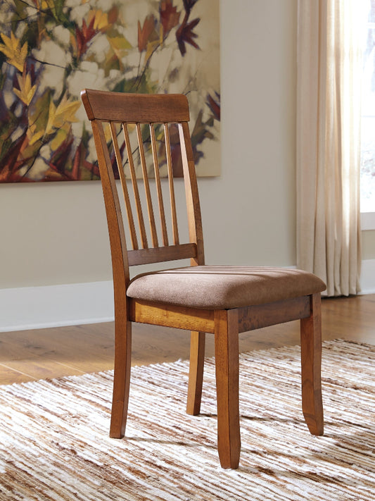 Wooden chair with a cushioned seat in a room with a painting and curtains.
