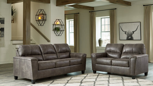 Brown leather sofa and loveseat set in a living room with decorative elements.