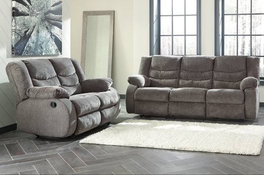 Gray reclining sofa set in a living room with large windows.