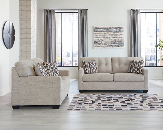 Beige sofa set in a living room with a rug and decorative pillows.