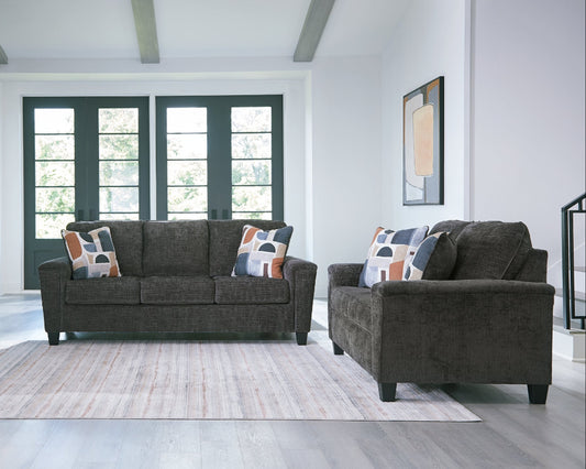 Living room with a gray sofa and loveseat and decorative pillows on a light gray rug.