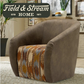 A brown upholstered barrel-style armchair with a patterned seat cushion in rust, beige, and blue tones, shown in a living room setting with a Field & Stream Home logo overlay in the top left.