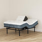 Adjustable bed with mattress and pillow on a wooden floor against a beige wall