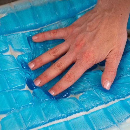 Hand pressing into a blue gel