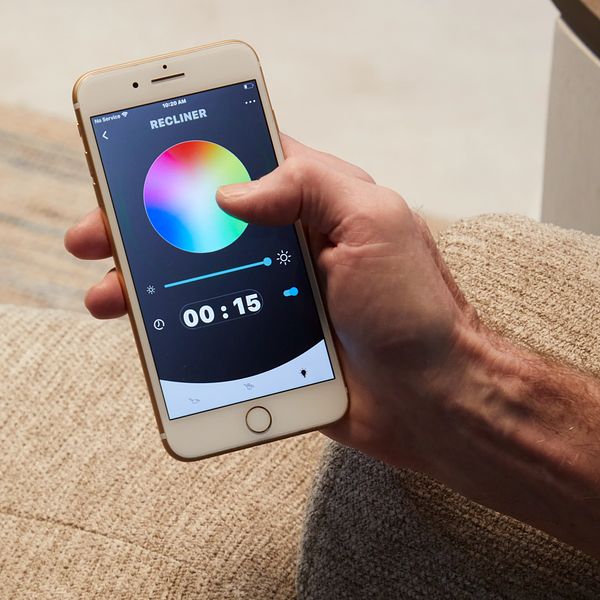 Hand holding a smartphone with a color selection app on a carpeted floor