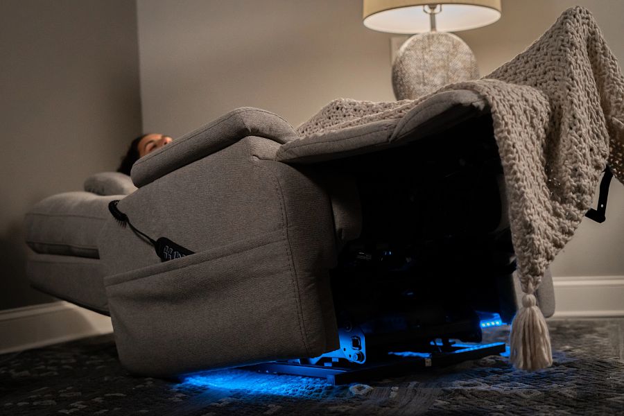 Gray recliner chair with a blanket and blue LED lights in a dimly lit room.