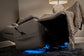 Gray recliner chair with a blanket and blue LED lights in a dimly lit room.