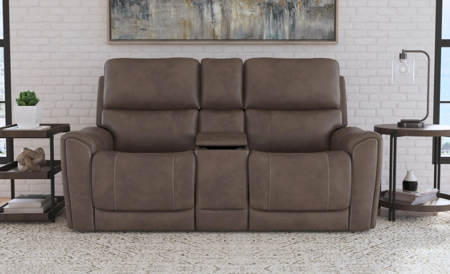 Brown leather sofa in a living room setting with a white brick wall and abstract art.