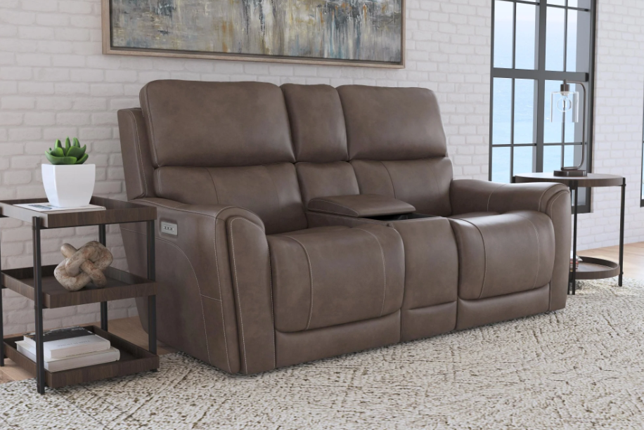 Brown leather reclining sofa in a living room setting with side tables and decor.