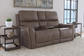 Brown leather reclining sofa in a living room setting with side tables and decor.