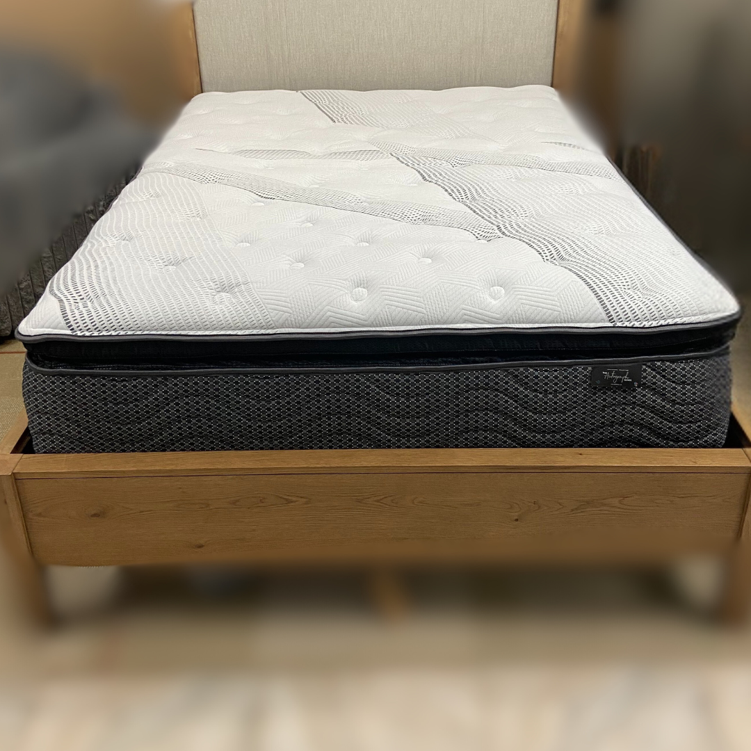 Gray mattress on a wooden bed frame with a blurred background