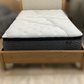 Gray mattress on a wooden bed frame with a blurred background