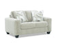 cream loveseat with patterned cushions on a white background