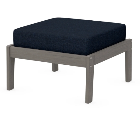 A navy cushioned deep seating ottoman with a driftwood frame, made from all-weather materials suitable for outdoor use.
