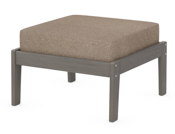 A beige cushioned deep seating ottoman with a driftwood frame, made from all-weather materials suitable for outdoor use.