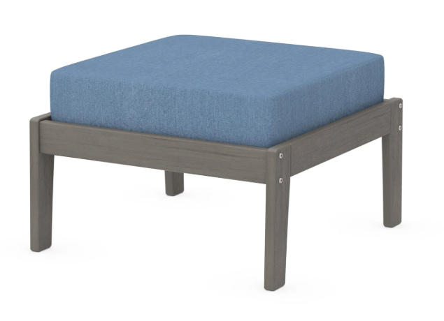 A blue cushioned deep seating ottoman with a driftwood frame, made from all-weather materials suitable for outdoor use.