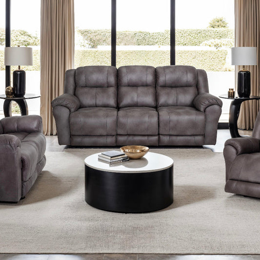 Gray leather sofa set in a living room with a round coffee table.