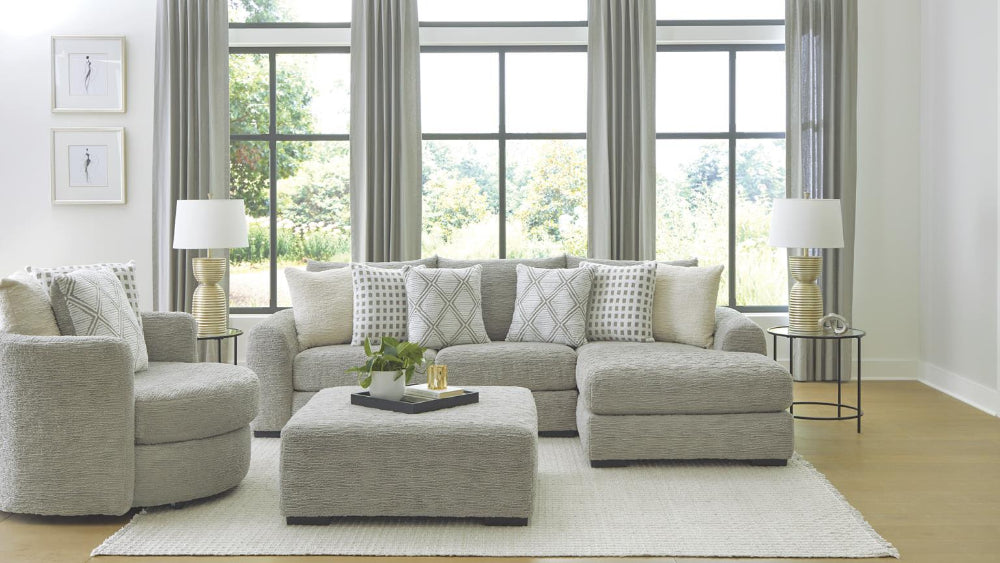 Living room with gray sectional sofa, ottoman, and decorative pillows.