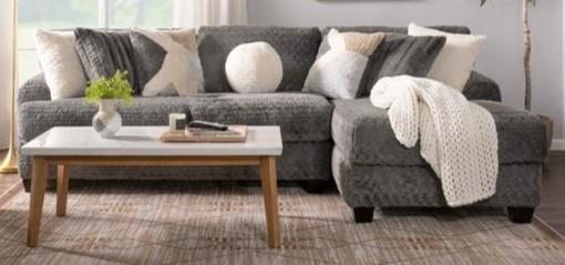 Gray sectional sofa with cushions and a coffee table in a living room setting.