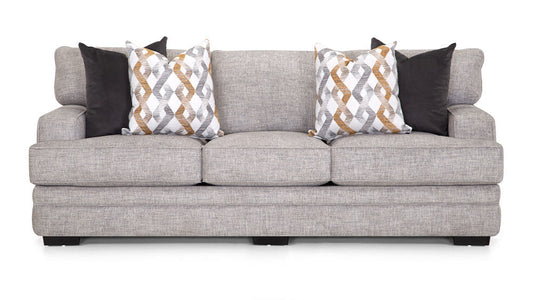 A beige upholstered Protege sofa with accent pillows featuring geometric patterns.