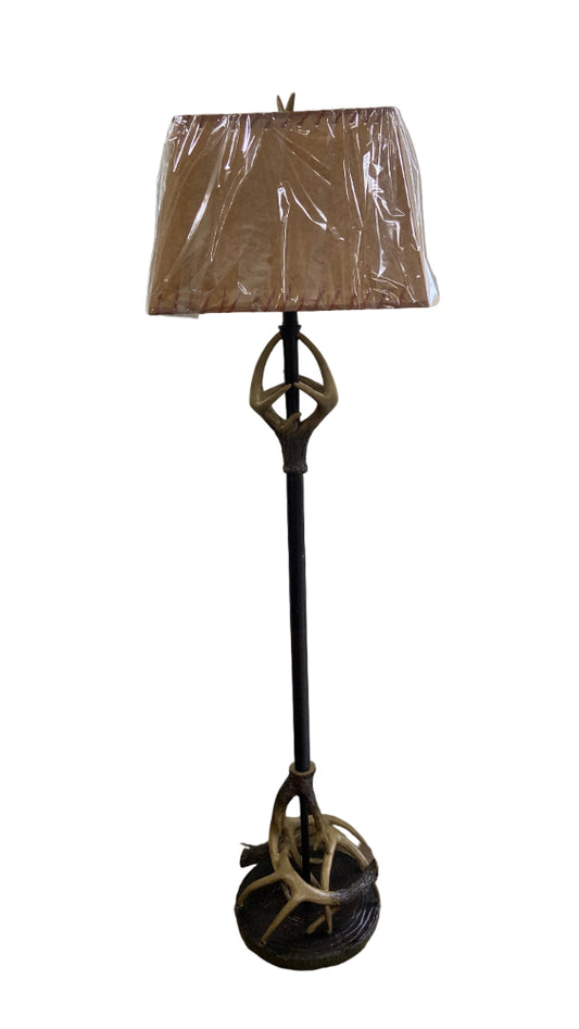 Floor lamp with decorative base of deer antlers and brown lampshade on a white background