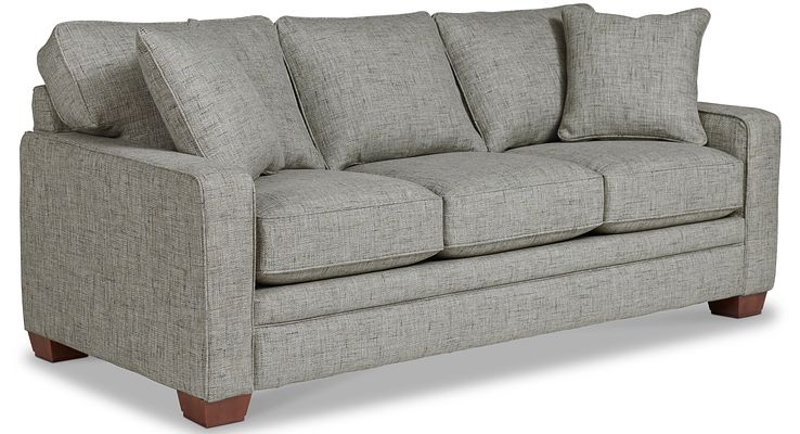 A contemporary sofa with clean lines, featuring track arms, decorative wood legs, and generously sized cushions.