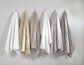Six textured bath towels in white, beige, light gray, and medium gray hang from black hooks on a light gray wall.