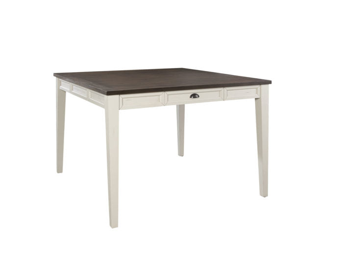 A modern farmhouse style counter table with a two-tone finish, having antiqued white legs and a dark oak tabletop, with a visible drawer on each side.
