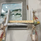 Decorative sign with 'Life is better in flip flops' on a white wall with a mirror and decorative elements.
