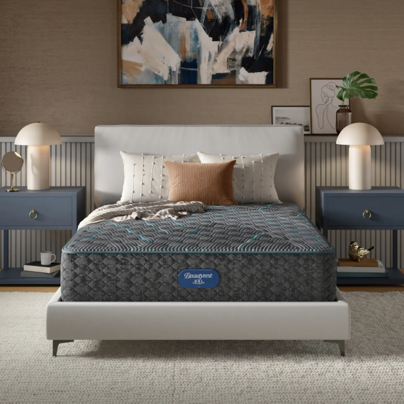Mattress on a bed in a bedroom setting with abstract art and lamps.